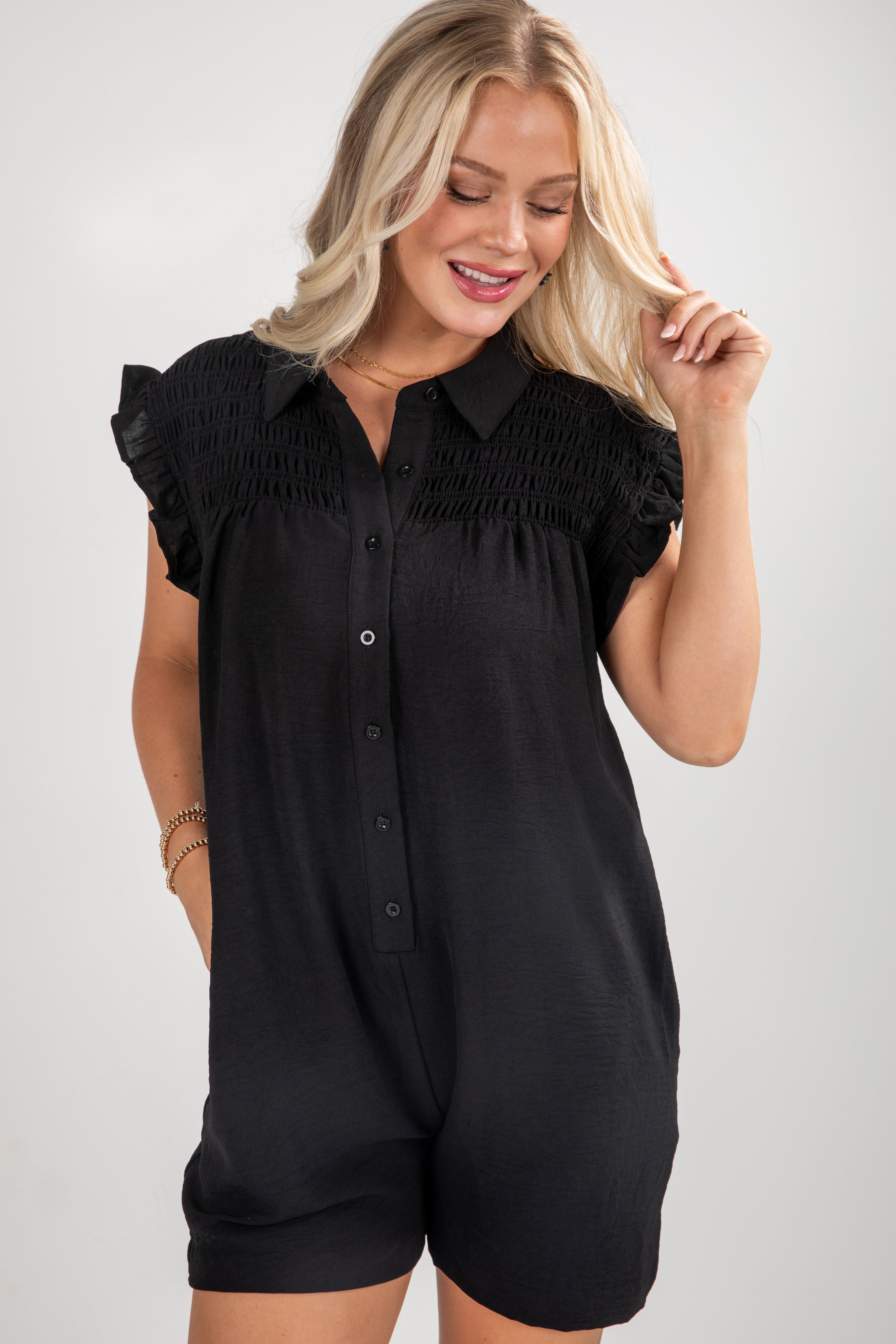 Woman wearing a black romper with a collar on a plain background