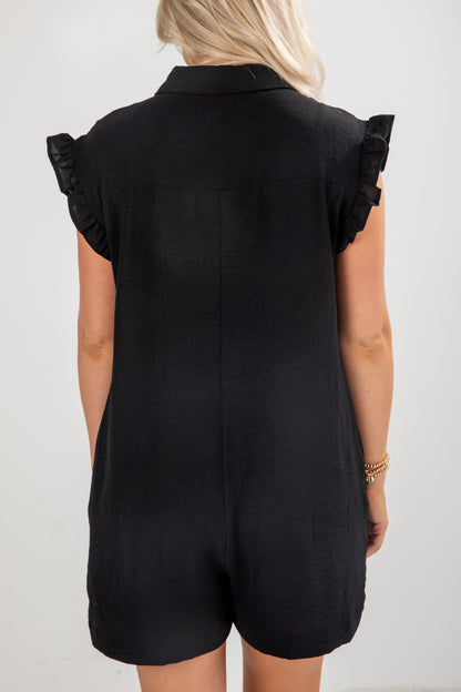 Black romper with ruffled sleeves worn by a person on a white background