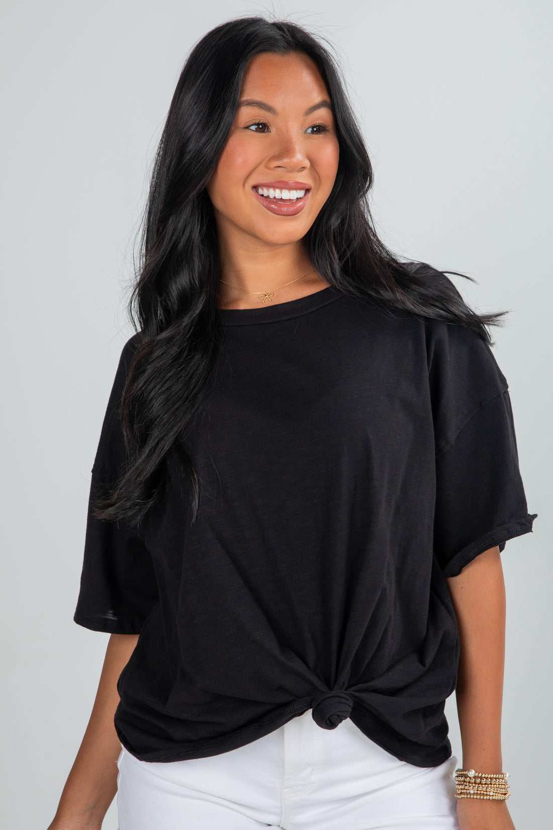 Woman wearing a black top with a knot detail on a plain background