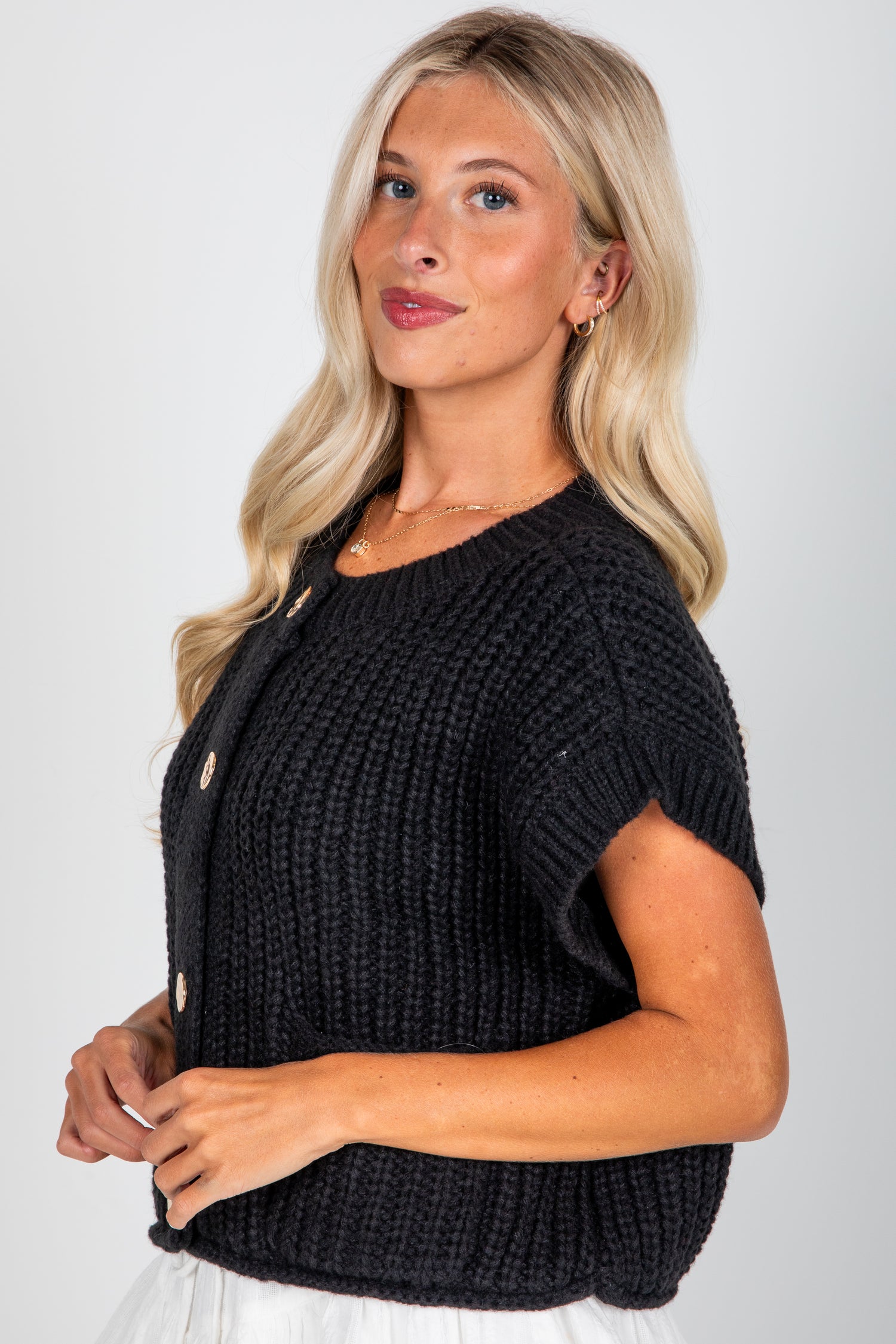Woman wearing a black knitted vest against a white background