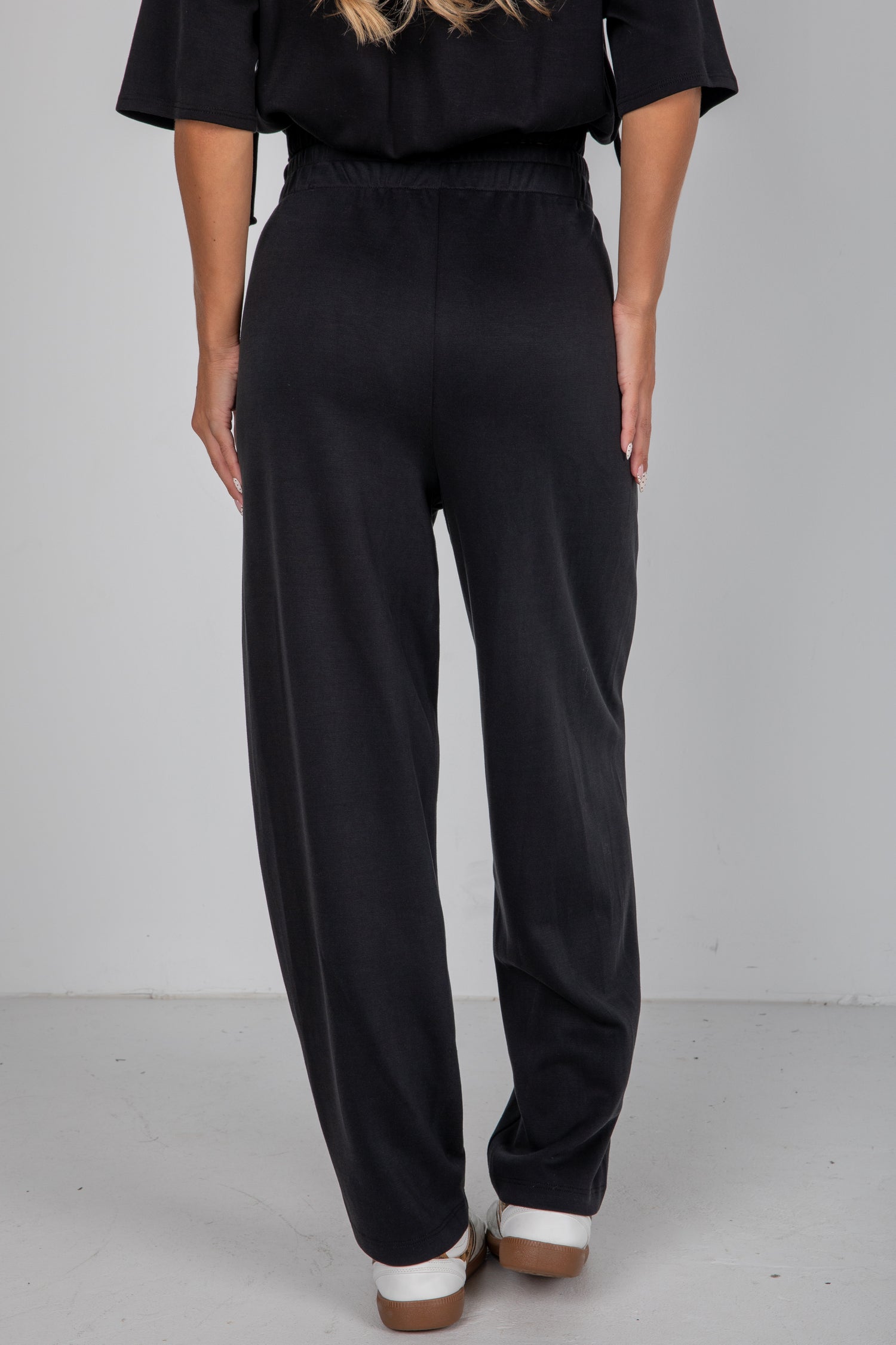 Person wearing black pants and a black top on a plain background