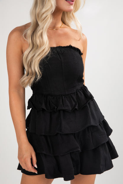 Black strapless ruffled dress worn by a model on a white background