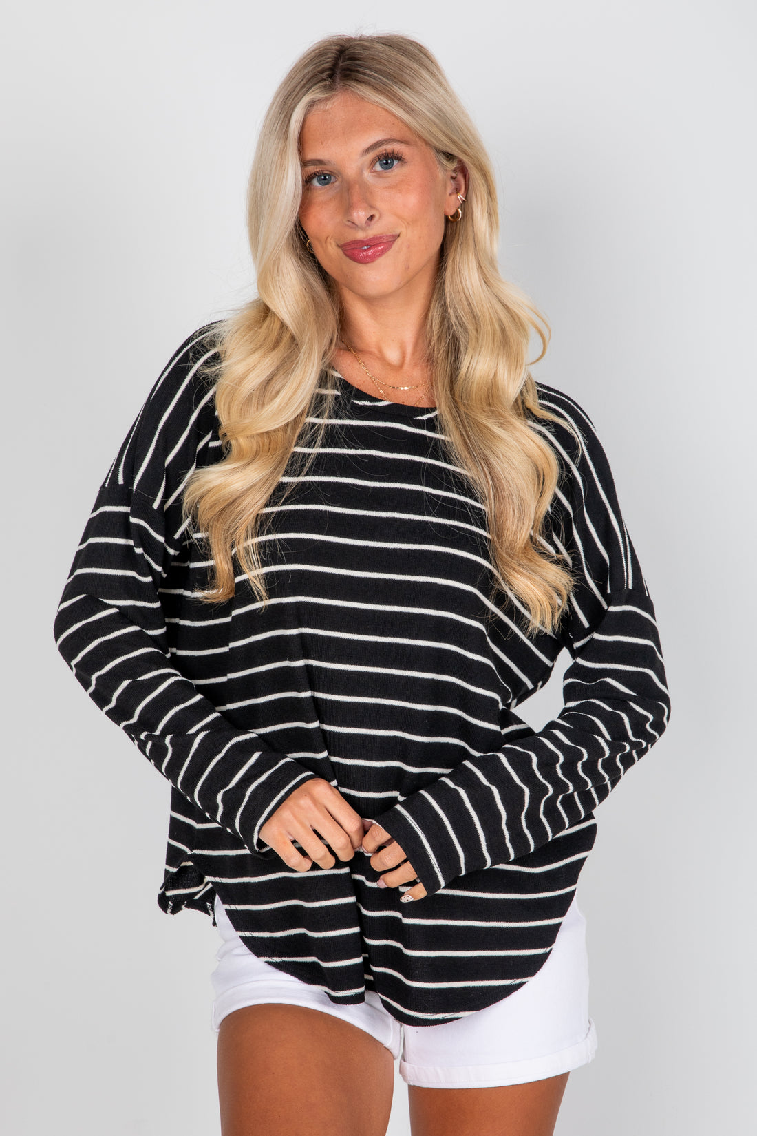 Woman wearing a black and white striped sweater with a plain background