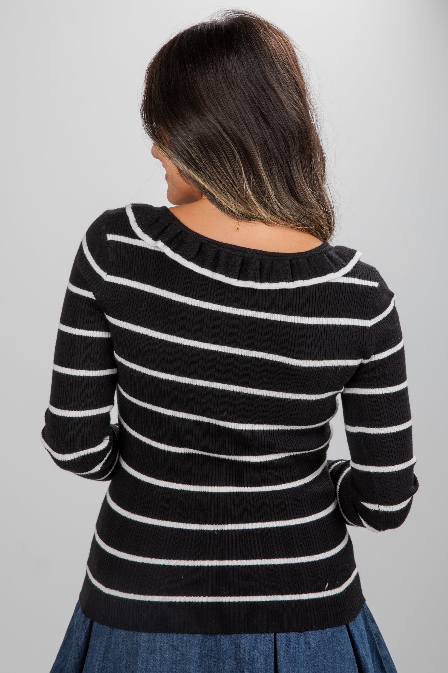 Person wearing a black and white striped sweater on a plain background