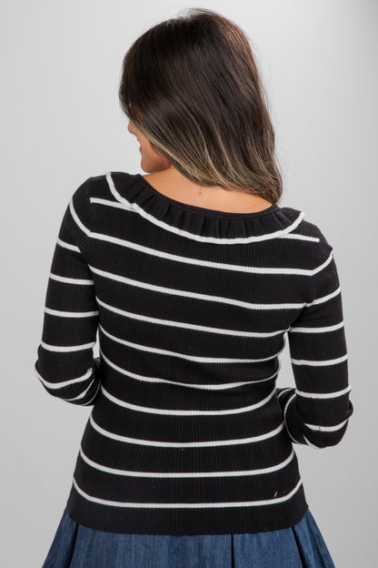 Person wearing a black and white striped sweater on a plain background
