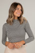 Woman wearing a gray striped long-sleeve top against a plain background