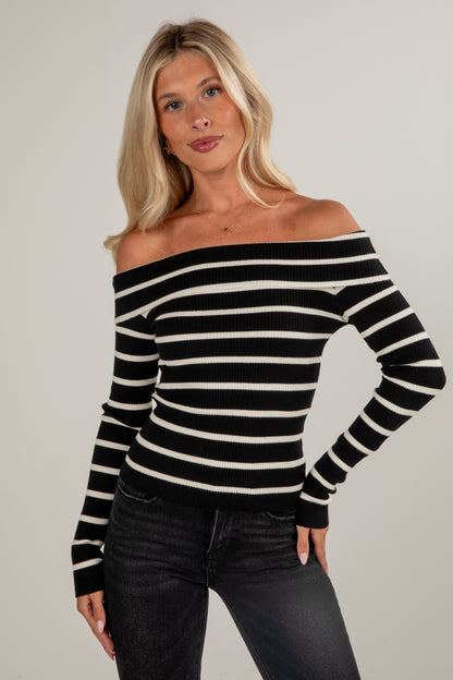 Woman wearing a black and white striped sweater against a plain background