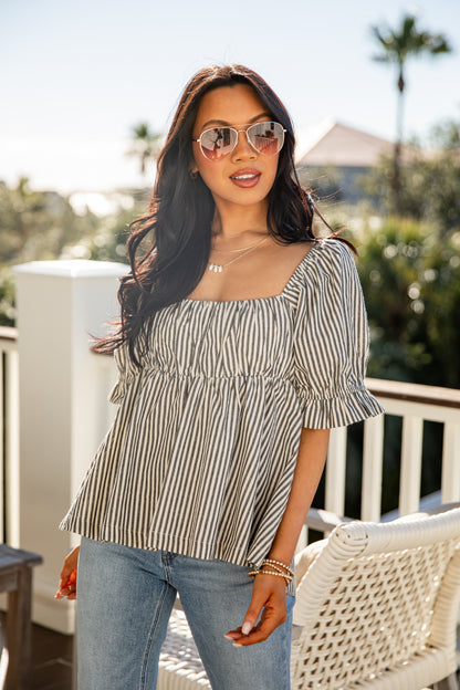 Woman wearing a striped shirt and sunglasses outdoors with blurred background