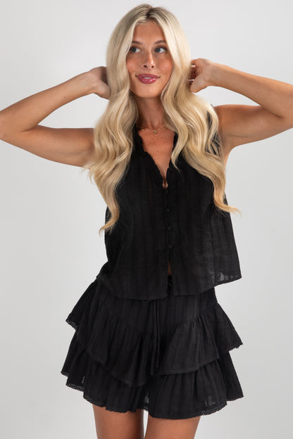 Woman wearing a black layered romper against a plain background