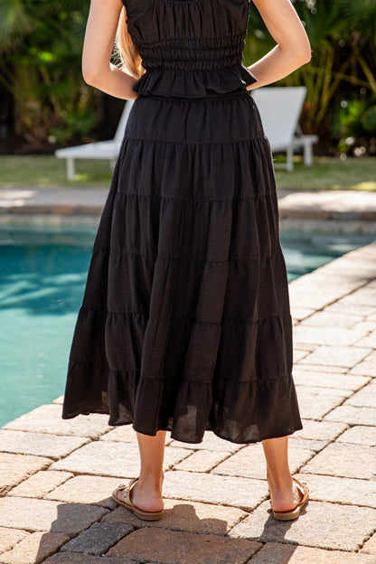 Person wearing a black tiered dress by a poolside