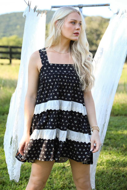 Woman wearing a black and white dress standing outdoors with mountains in the background