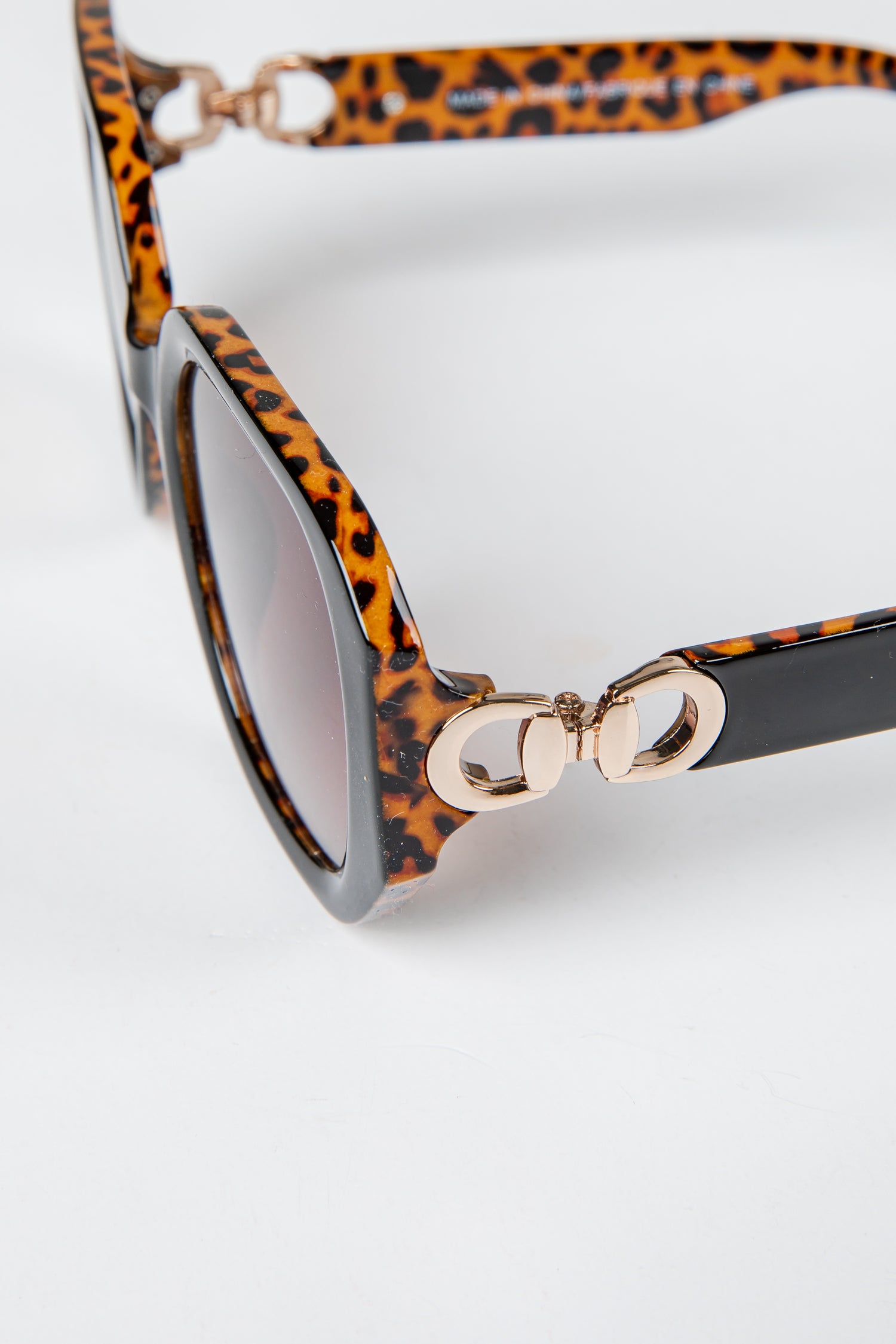 Leopard print sunglasses with gold accents on a white background