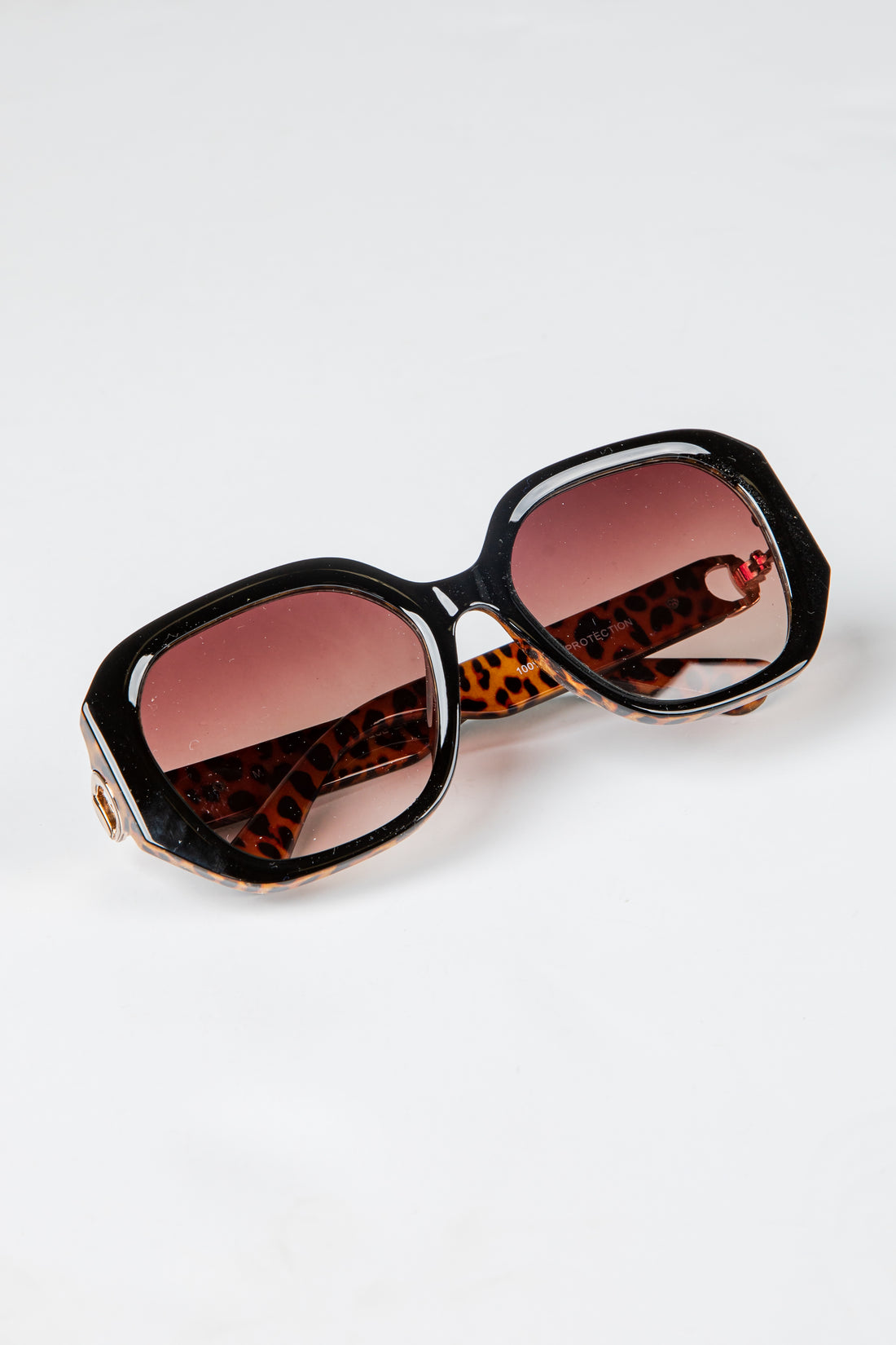 Sunglasses with leopard print frame and red lenses on a white background