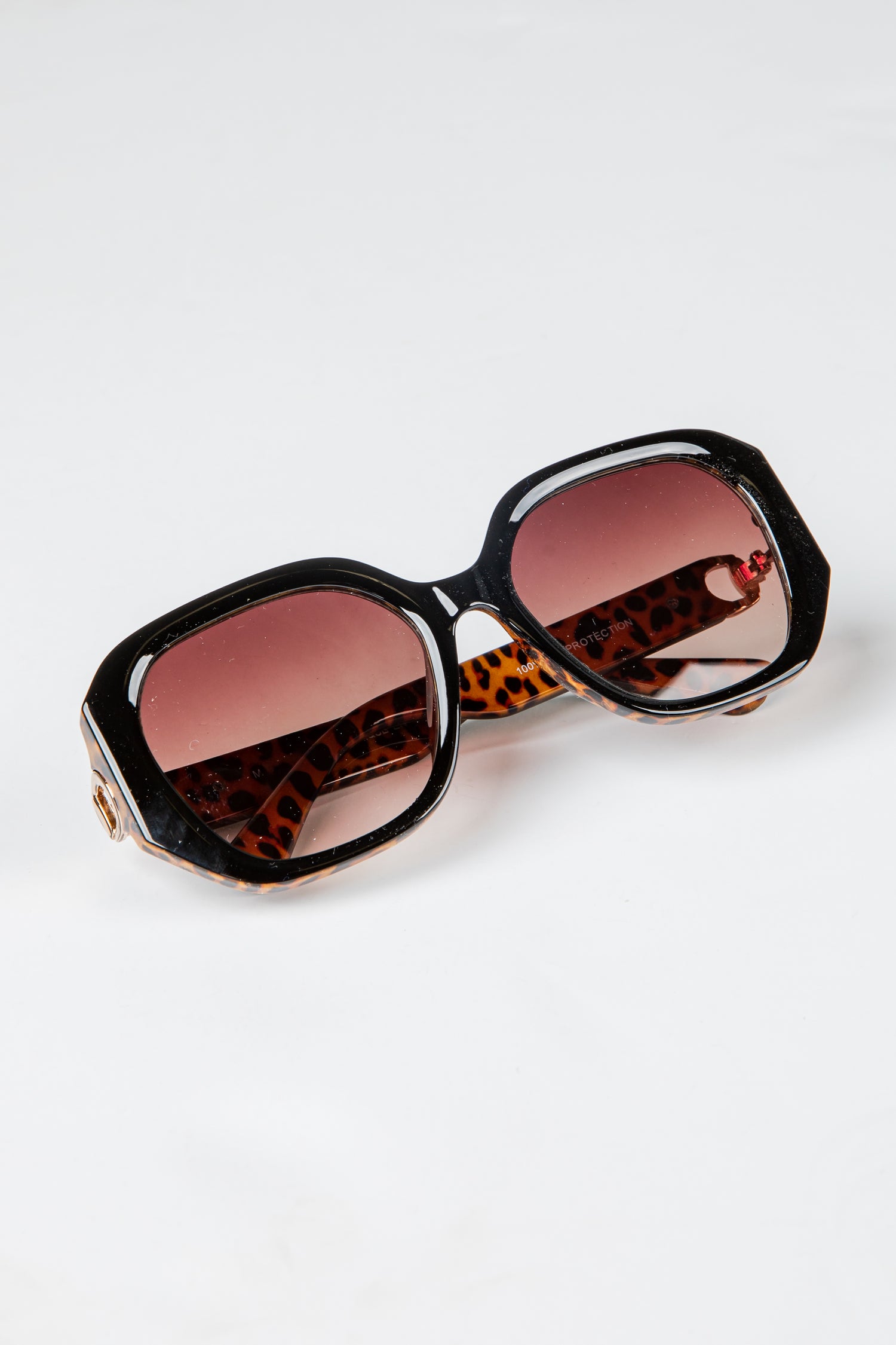 Sunglasses with leopard print frame and red lenses on a white background