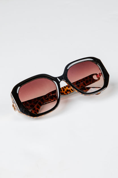 Sunglasses with leopard print frame and red lenses on a white background