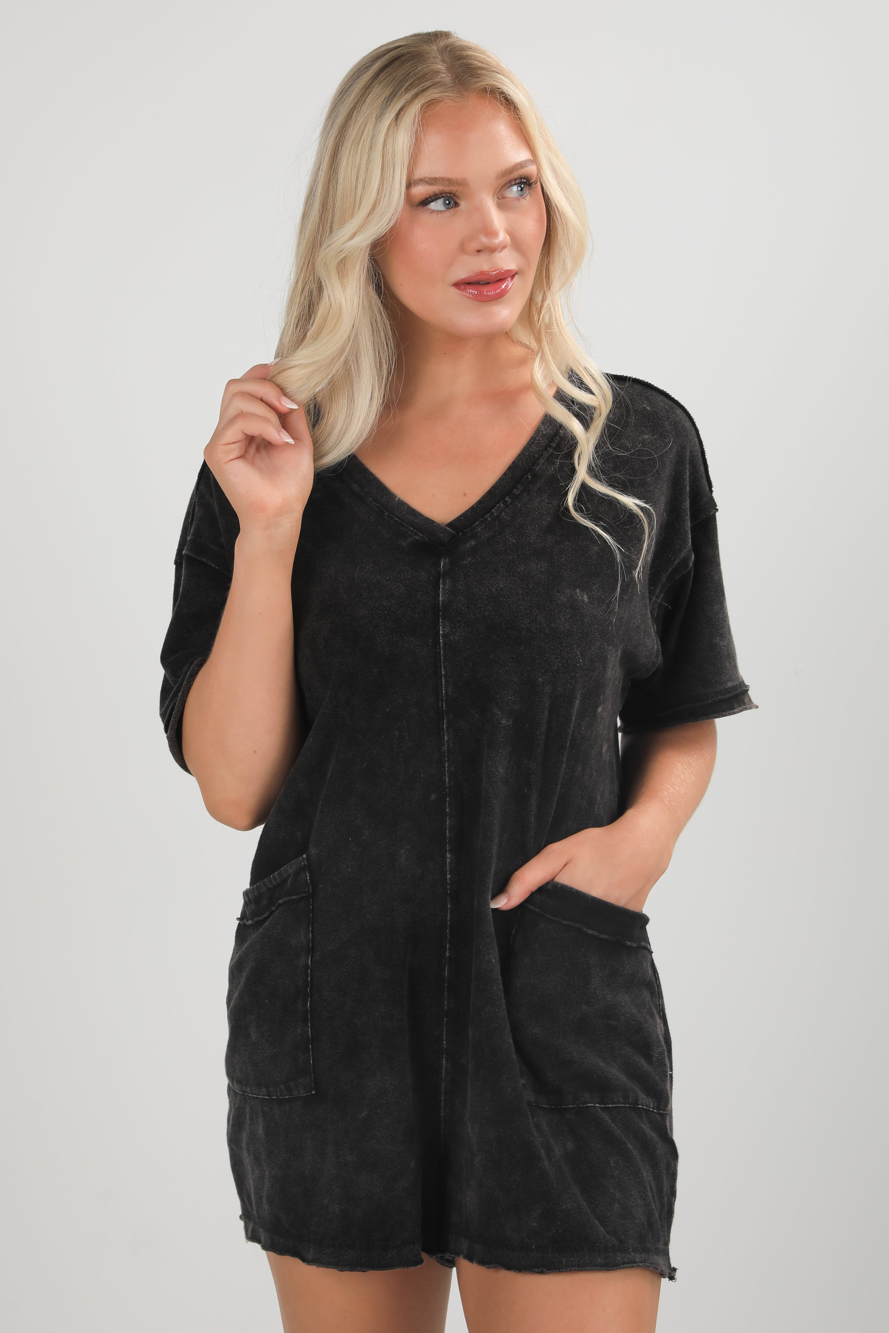 Woman wearing a black romper against a plain background