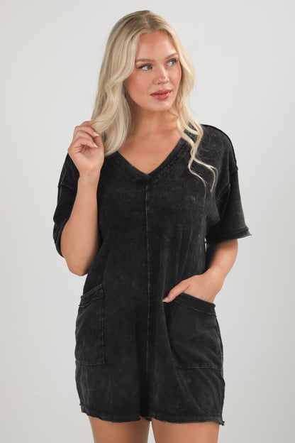 Woman wearing a black romper against a plain background