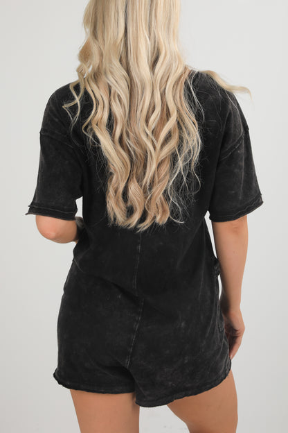 Person wearing a black distressed t-shirt and shorts set on a white background