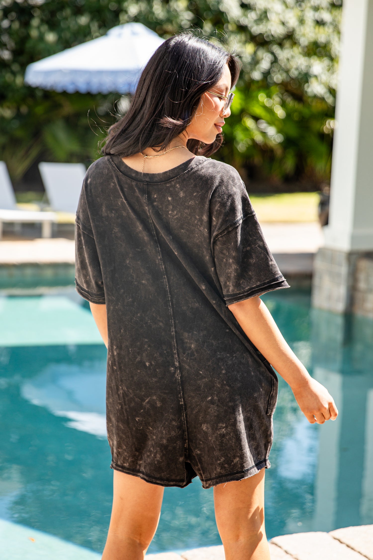 Woman wearing a black distressed t-shirt by a poolside