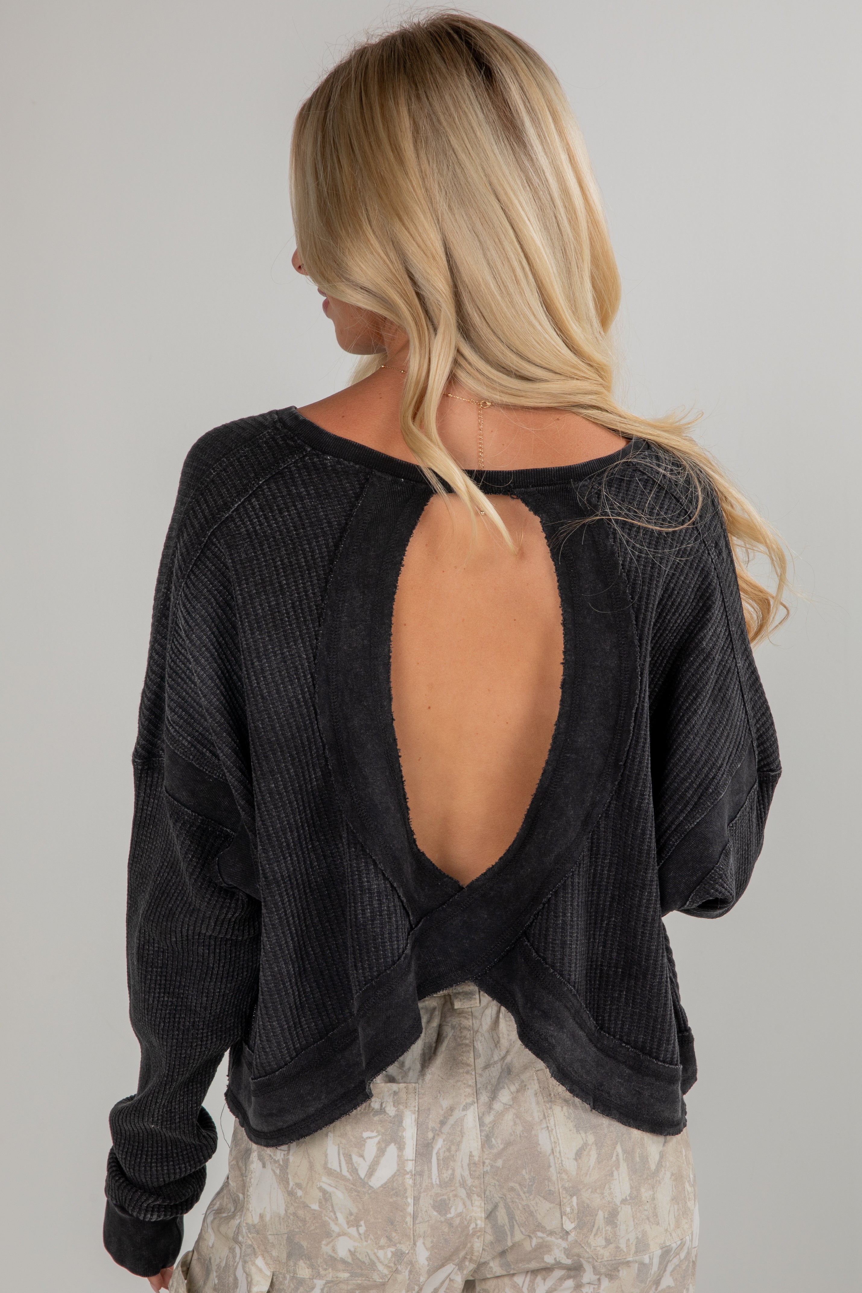 Black open-back sweater worn by a person on a plain background