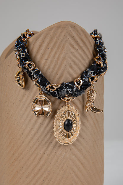 Decorative bracelet with gold and black elements on a beige stand