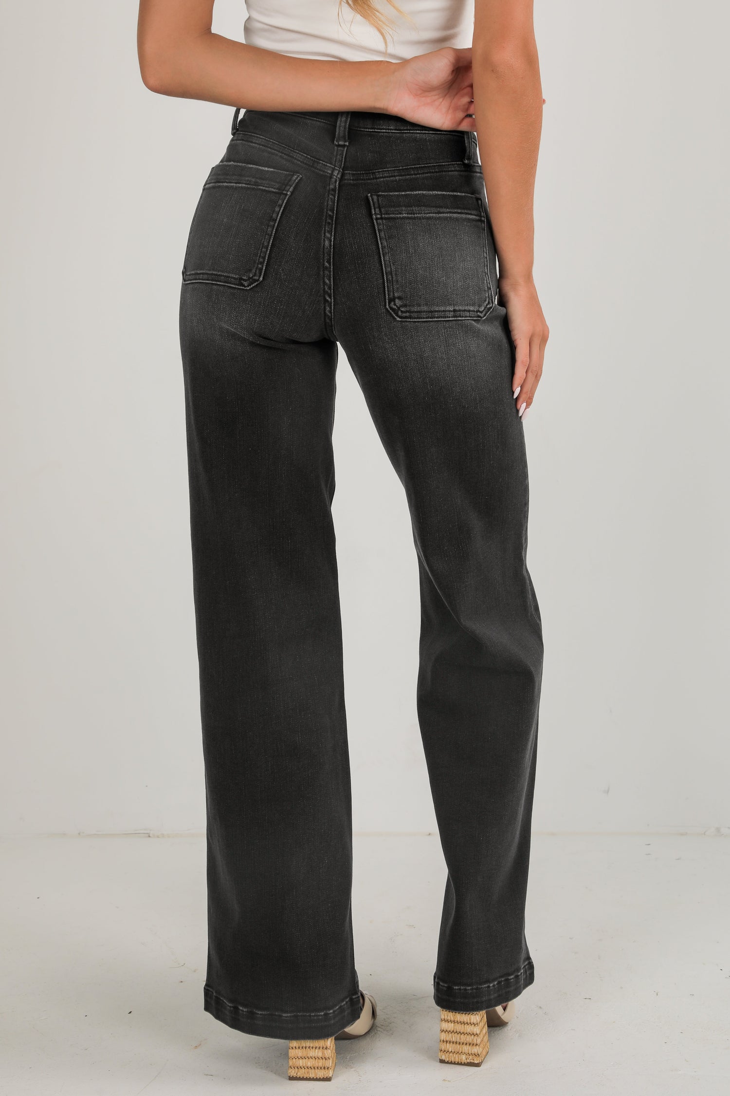Person wearing black jeans on a plain background