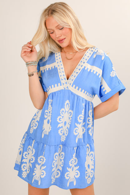 Woman wearing a blue dress with white patterns on a plain background