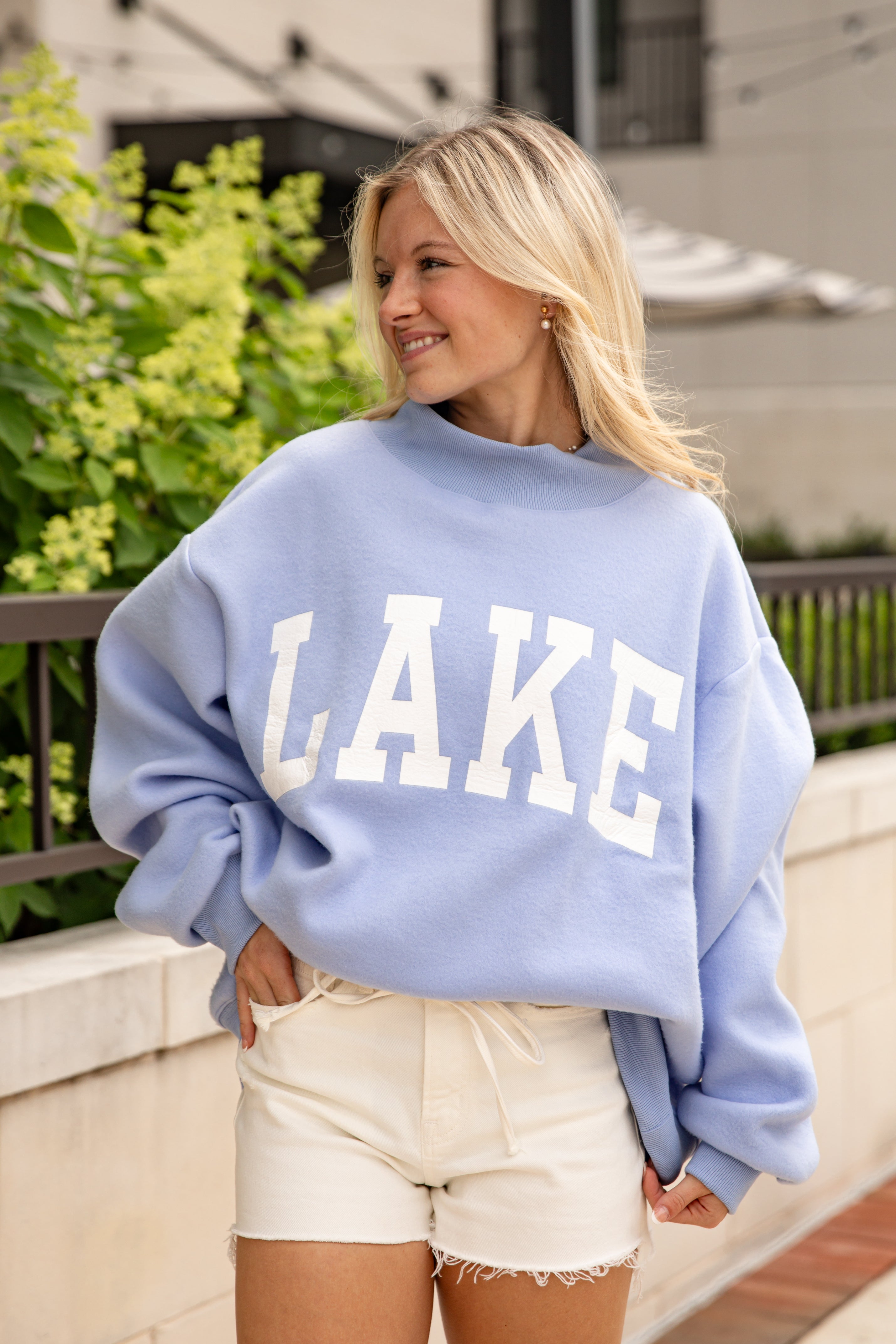 Woman wearing a light blue sweatshirt with &