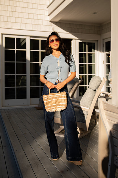 Woman holding a woven bag on a wooden deck