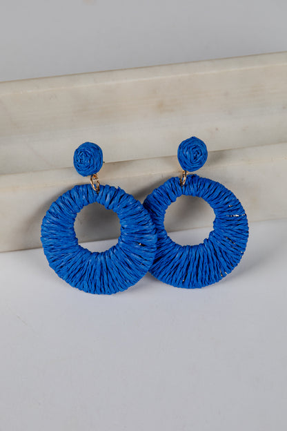 Blue hoop earrings on a light gray surface