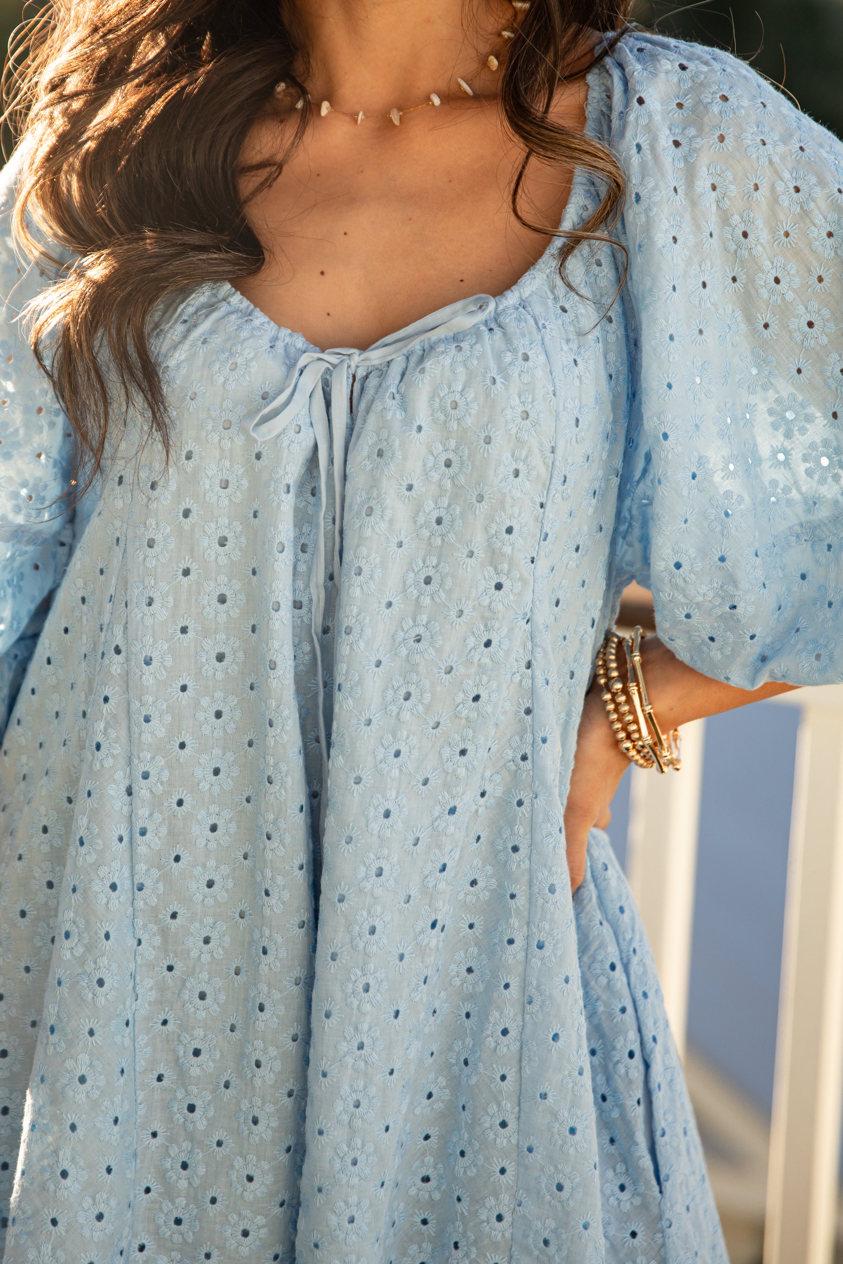 Light blue dress with black polka dots worn by a person, with a blurred background.