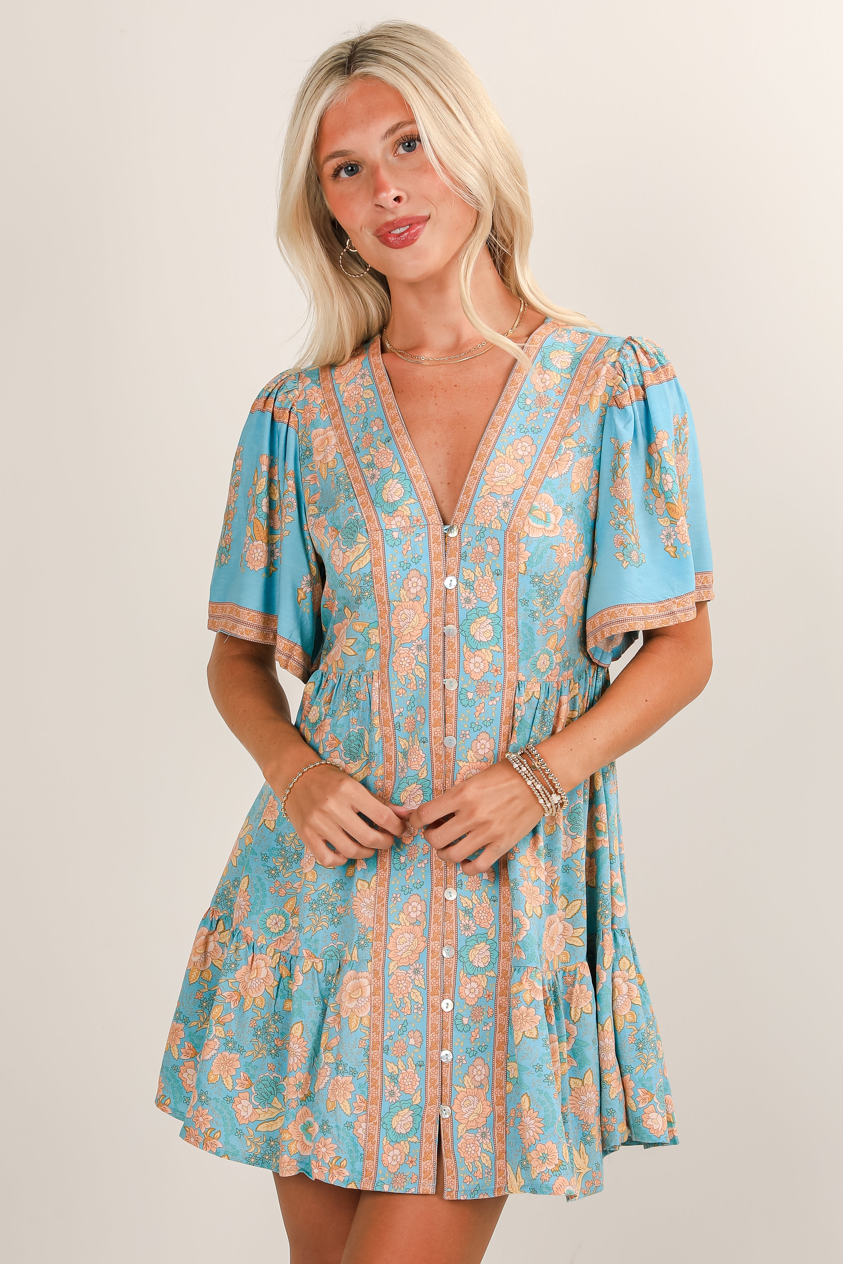 Woman wearing a blue and orange patterned dress on a plain background