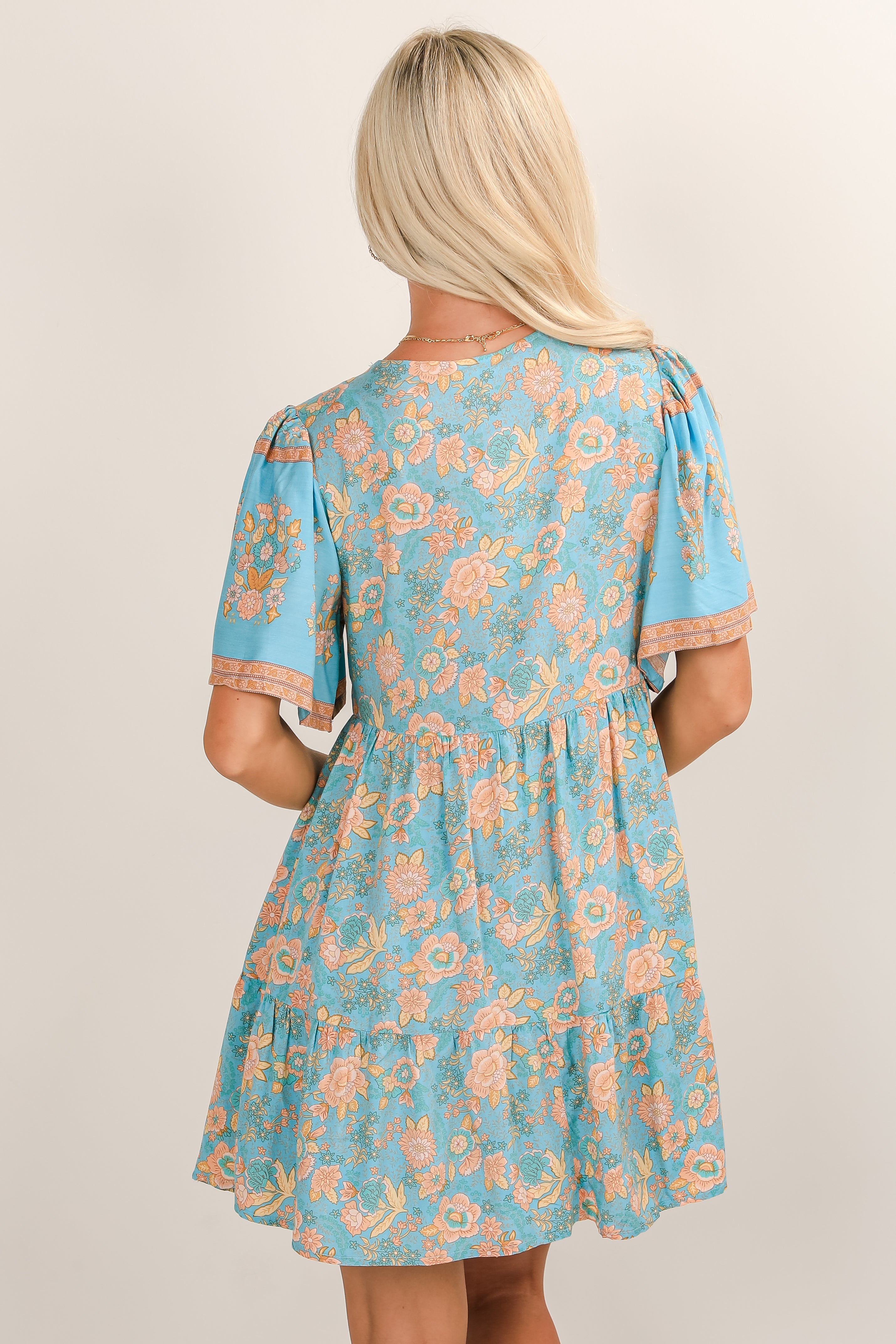 Woman wearing a blue floral dress against a plain background