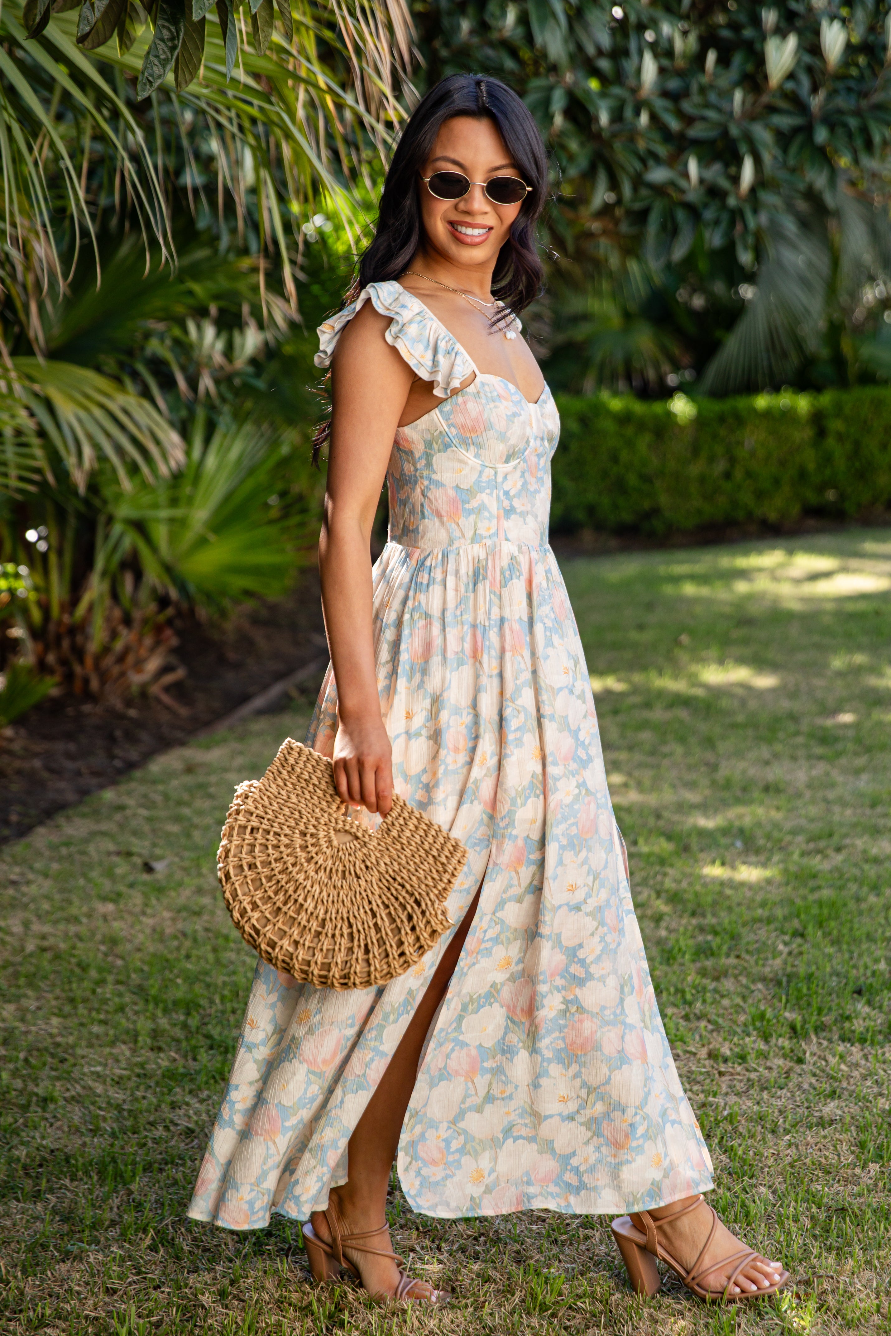 Woman in a floral dress holding a woven bag outdoors