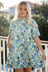 Woman wearing a floral dress on a balcony with greenery in the background