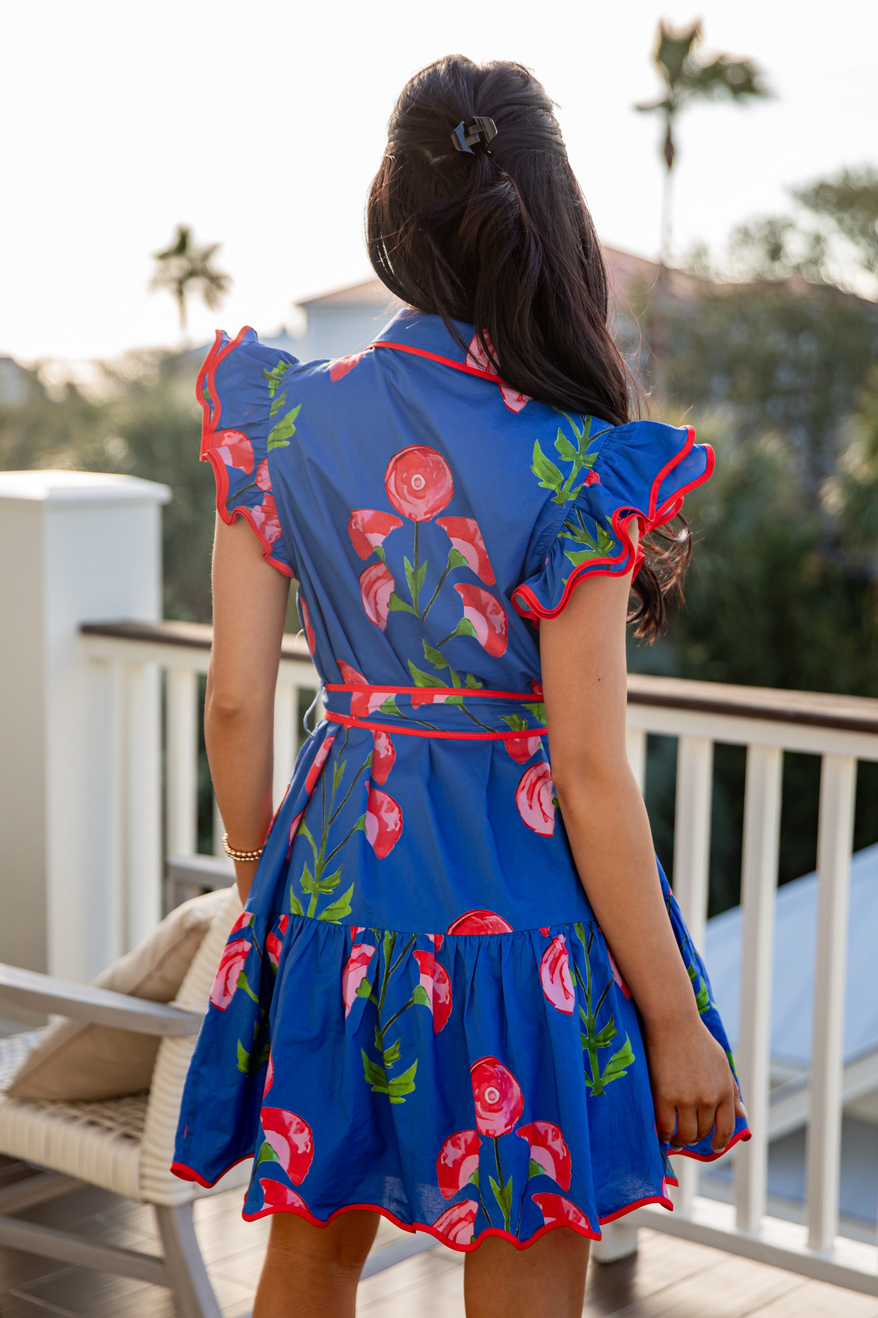 Woman wearing a blue floral dress on a balcony with blurred background