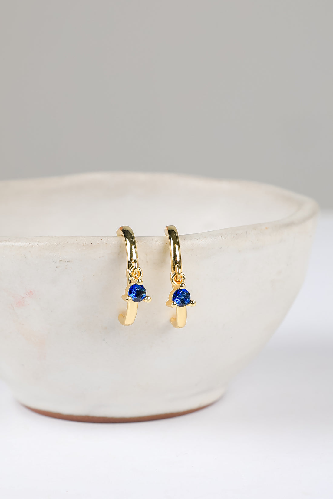 Gold earrings with blue gemstones on a white surface