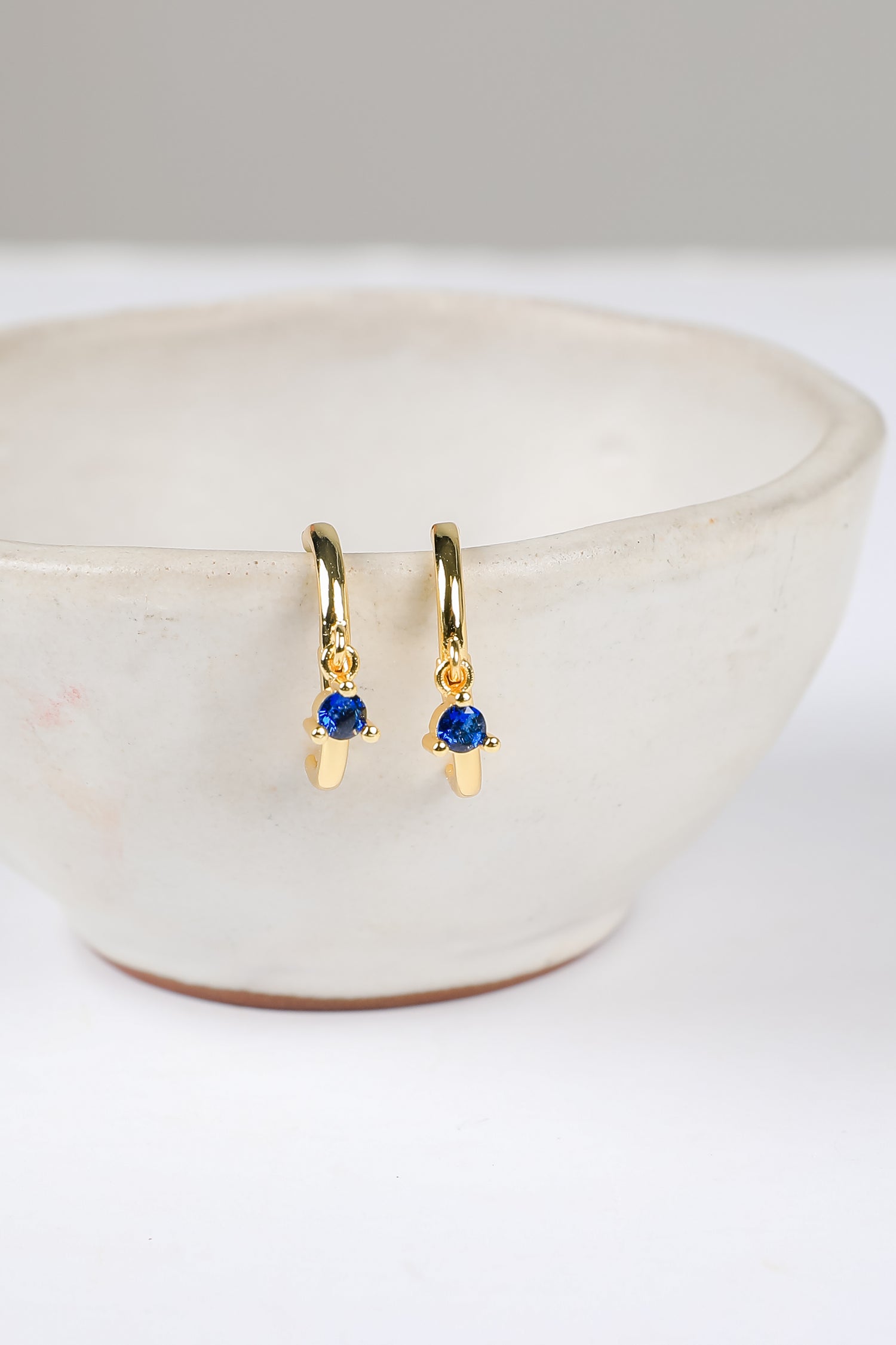Gold earrings with blue gemstones on a white surface