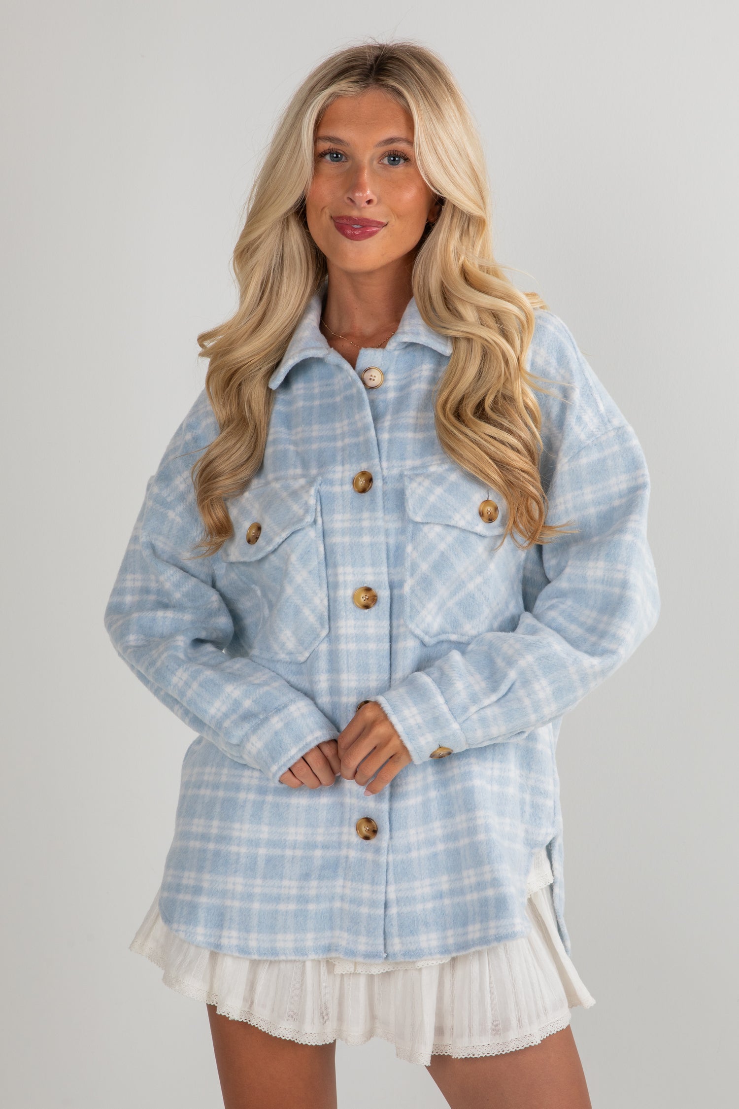 Woman wearing a light blue plaid jacket on a gray background
