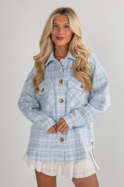 Woman wearing a light blue plaid jacket on a gray background