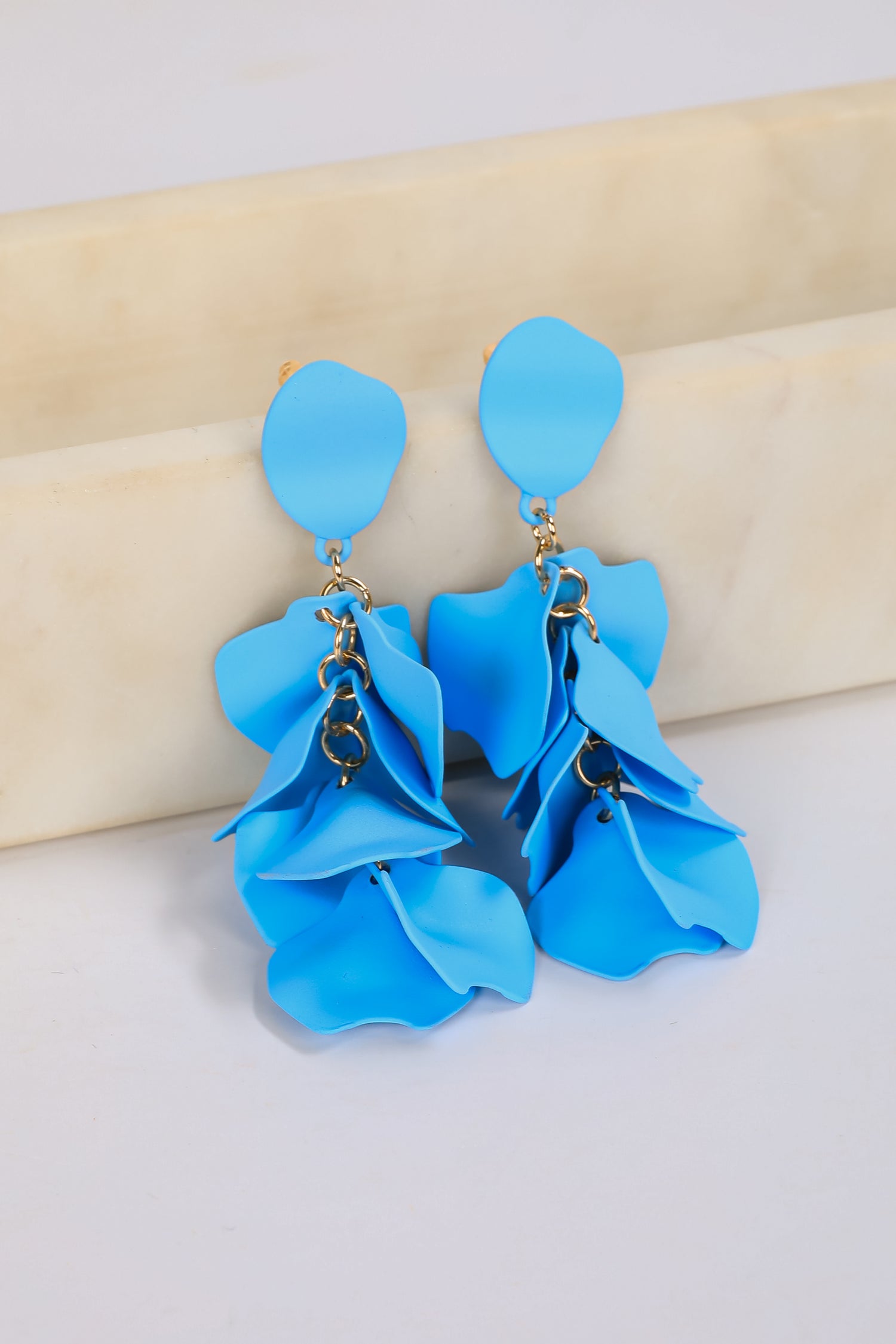 Blue floral earrings on a beige and white background