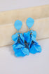 Blue floral earrings on a beige and white background