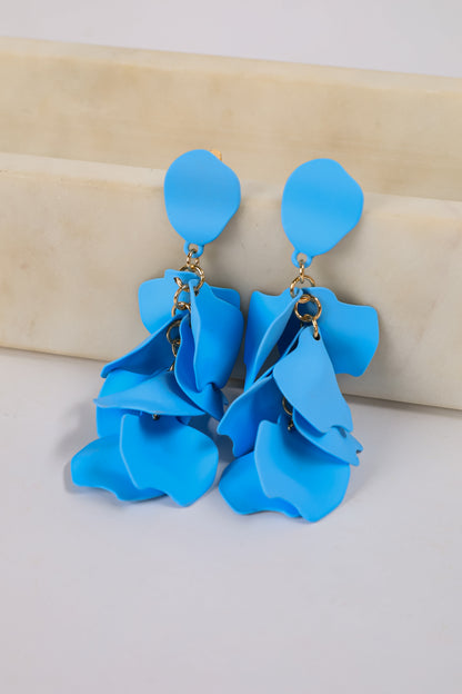 Blue floral earrings on a beige surface