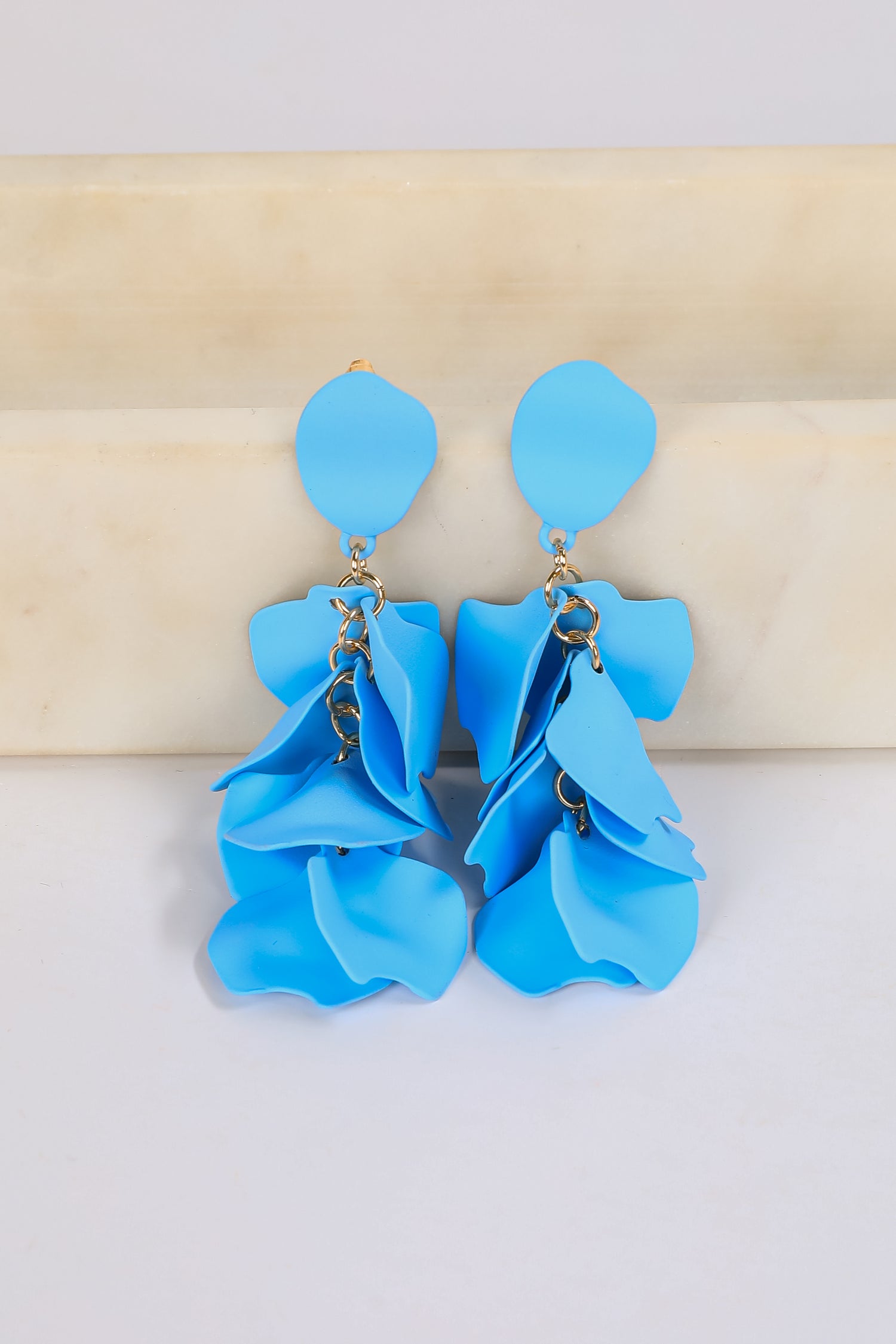 Blue floral earrings on a beige and white background