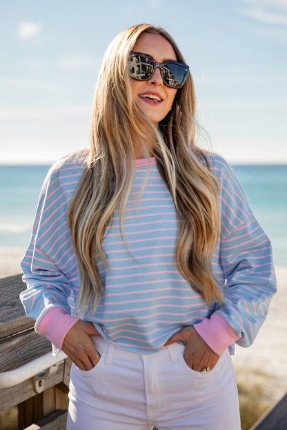 Woman wearing a striped shirt and sunglasses by the beach