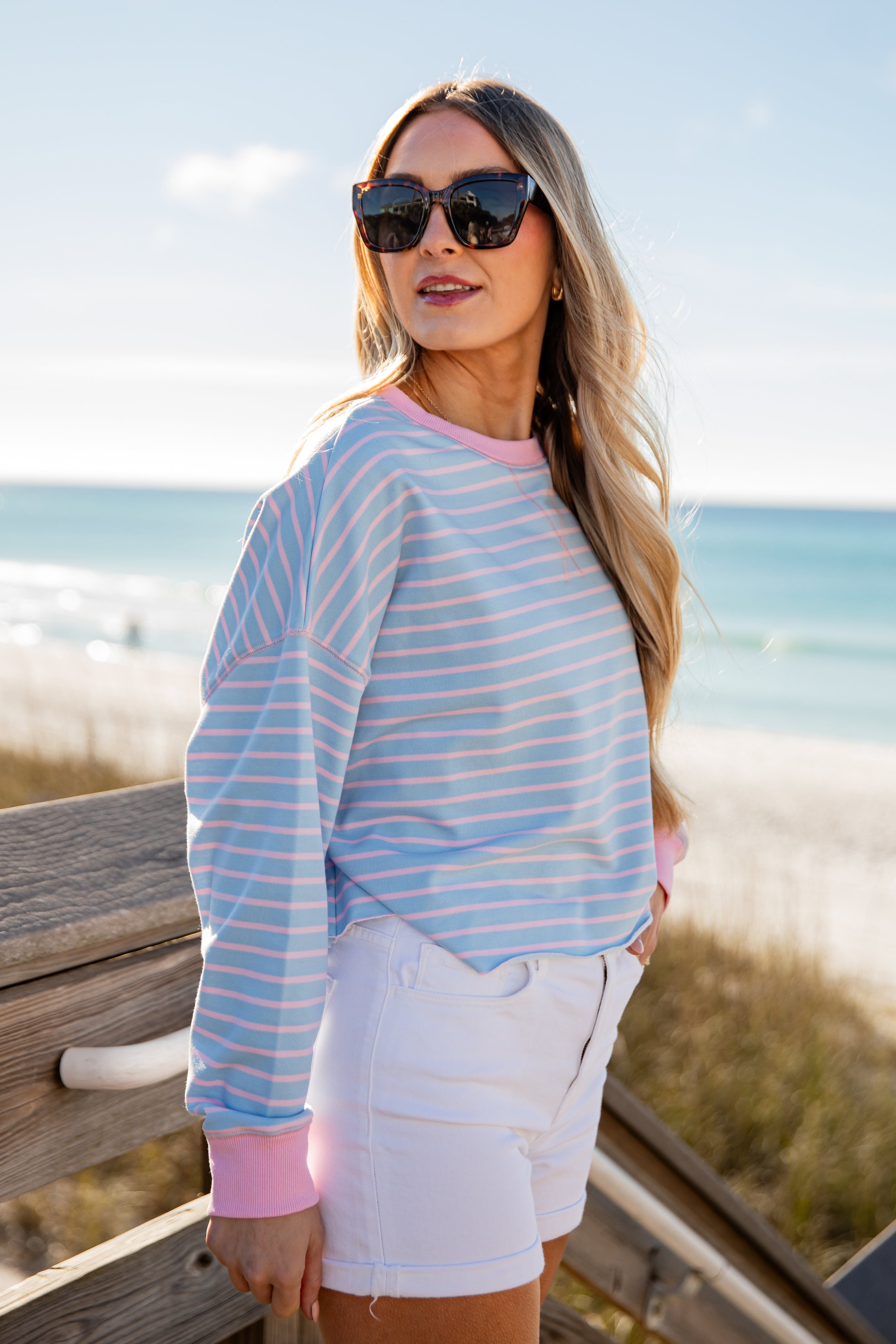 Woman wearing a striped shirt and sunglasses by the beach