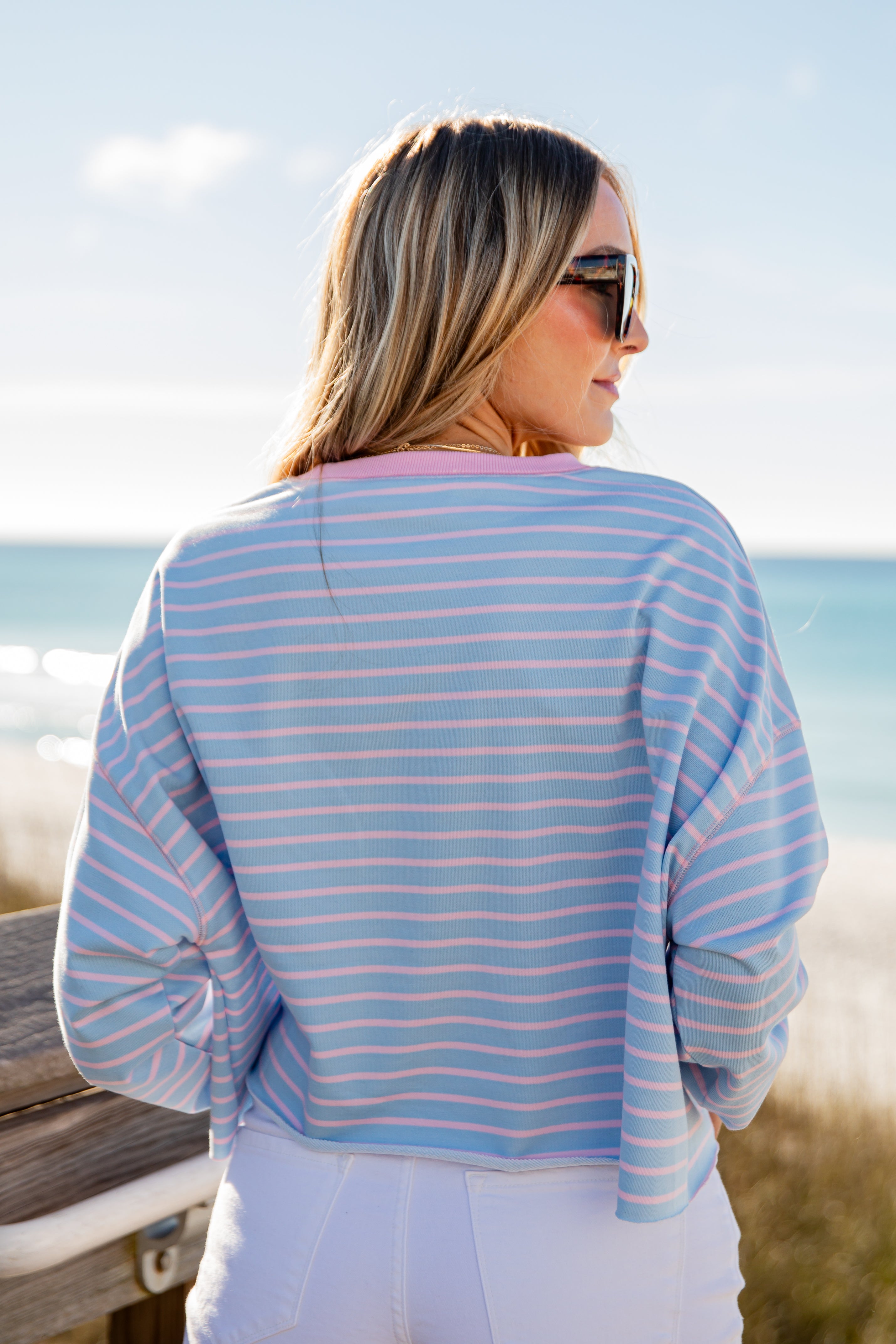 Woman wearing a blue and pink striped shirt by the beach