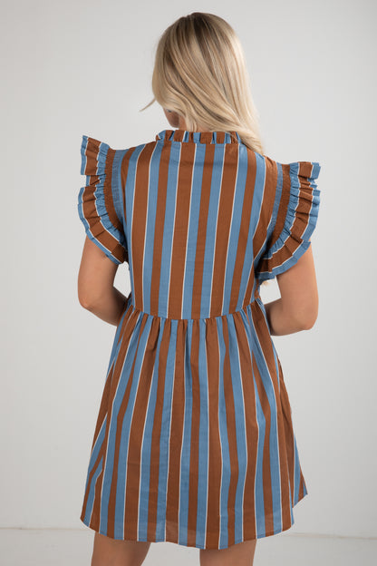 Woman wearing a brown and blue striped dress with ruffled sleeves against a white background