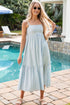 Woman in a striped dress standing by a pool