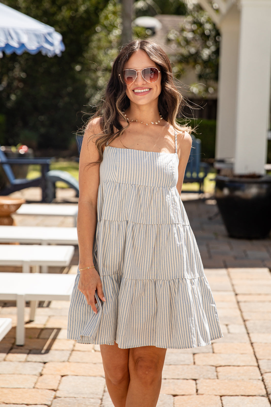 Woman wearing a striped dress standing outdoors on a sunny day.